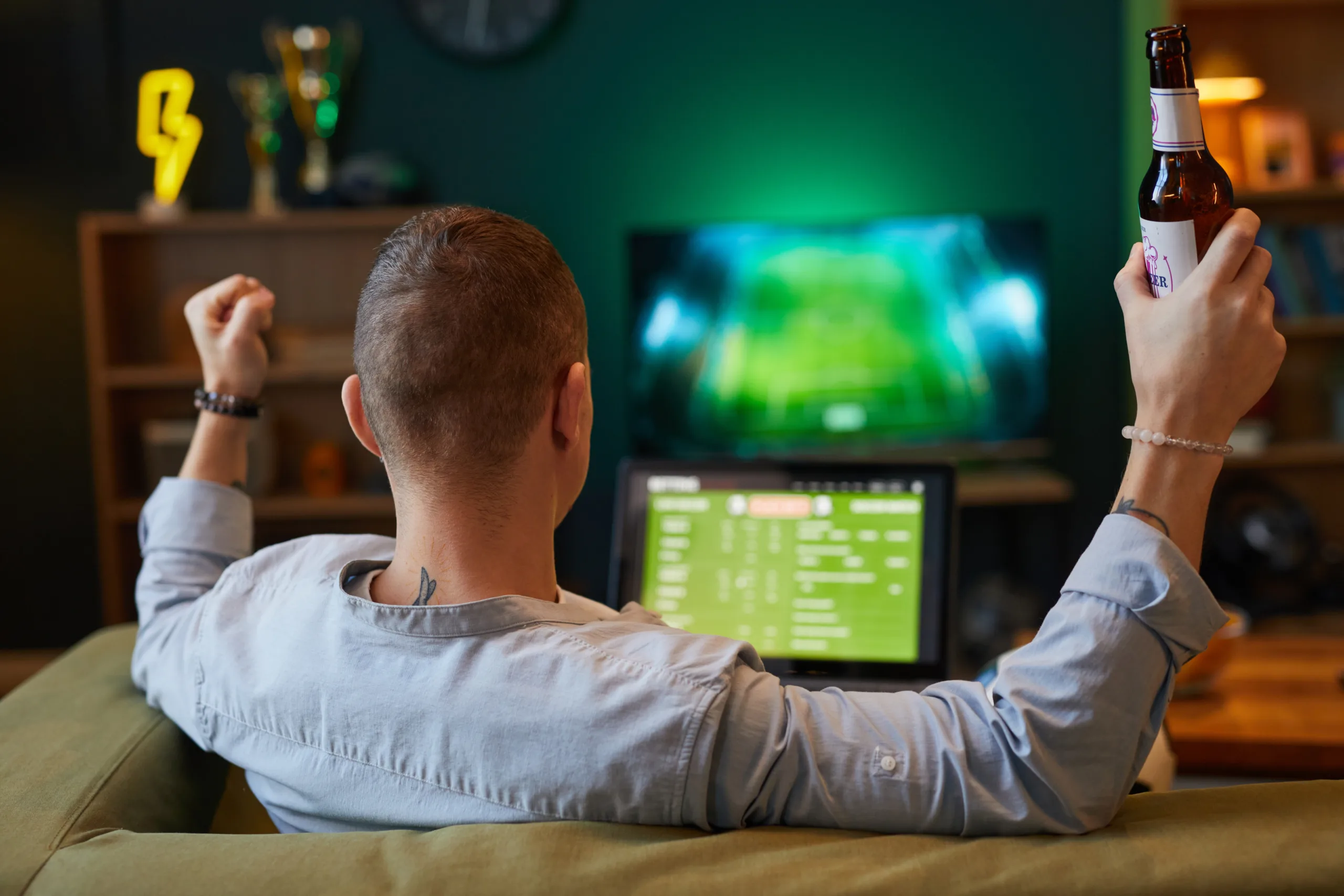 Celebrating Goal in Front of Television With Beer Bottle