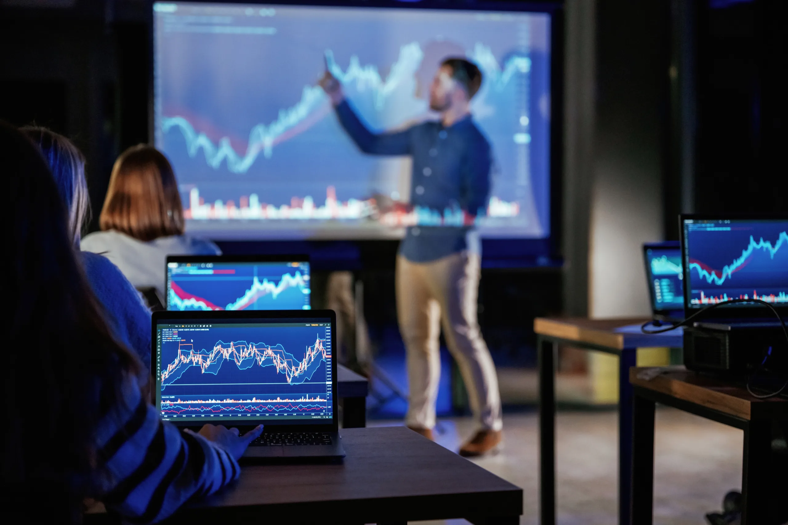Graph is going up. Male business trainer is against projector with data, teaching people