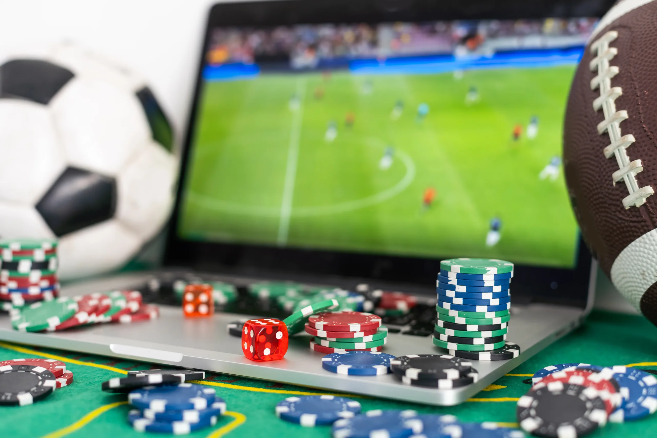 Close up cropped shot of male hands making bets using gambling mobile application on his phone. Man watching football match online broadcast on his laptop waiting for winning results.